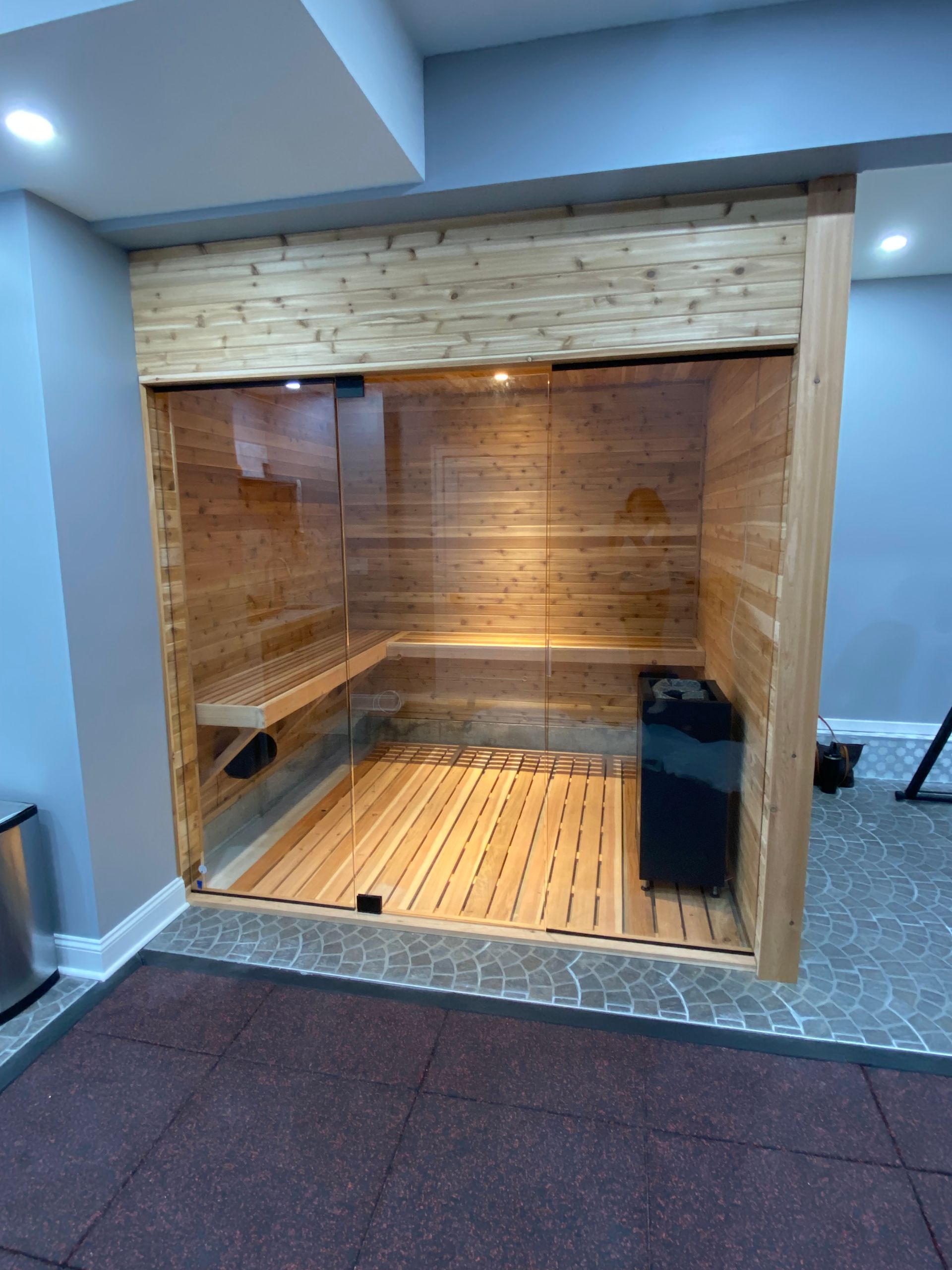 Wood-lined indoor sauna with benches and warm lighting in a modern room
