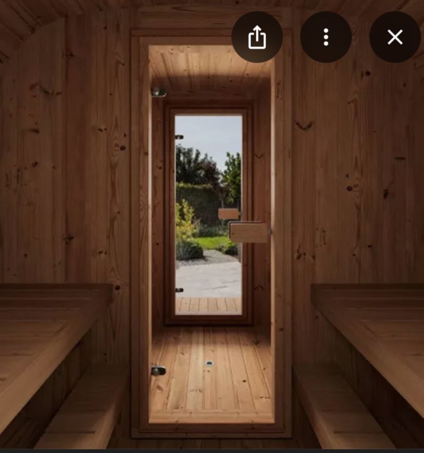 Wooden outdoor sauna barrel with benches, bucket, and stove inside