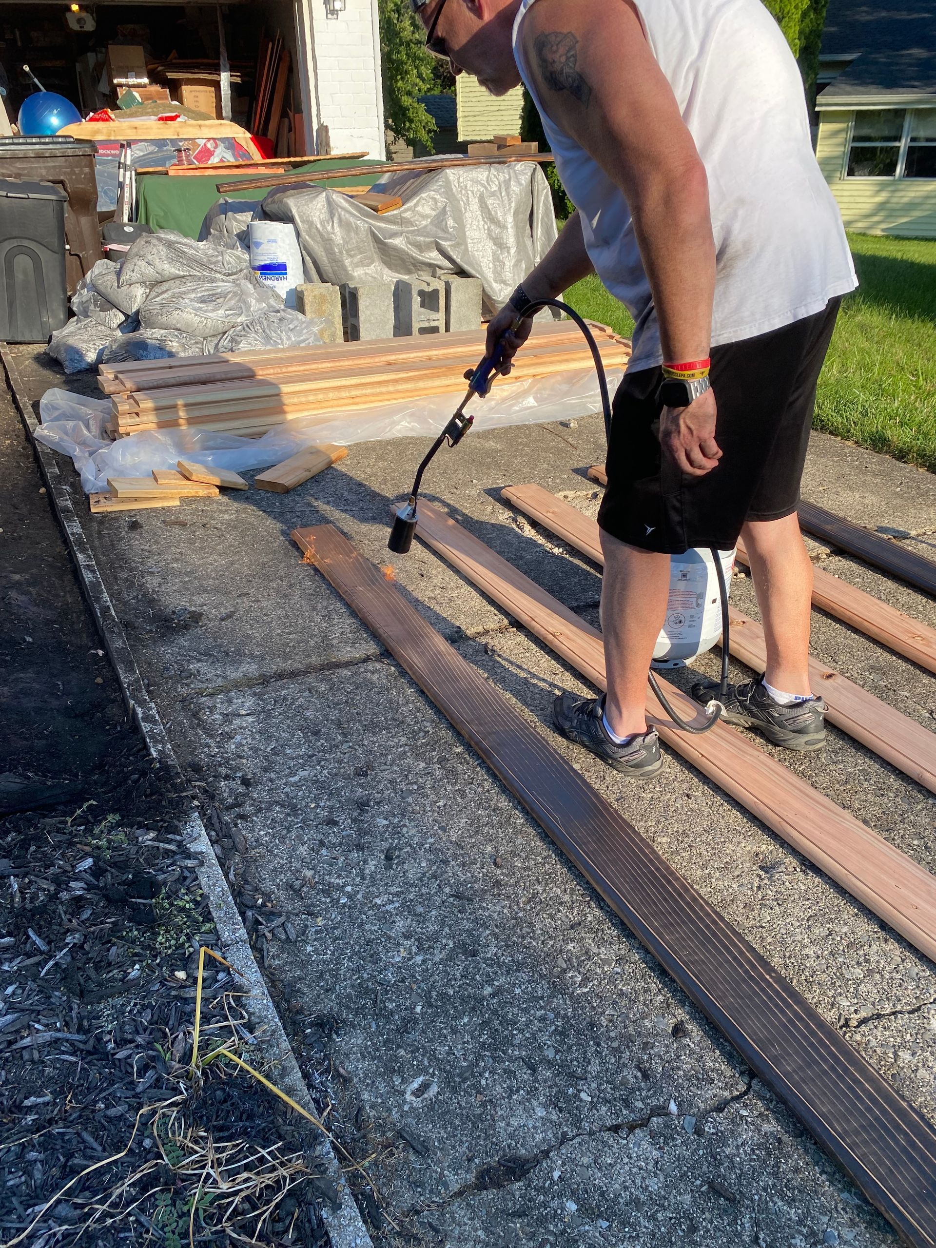 Worker spraying water on a gravel roof repair area with a hose wand