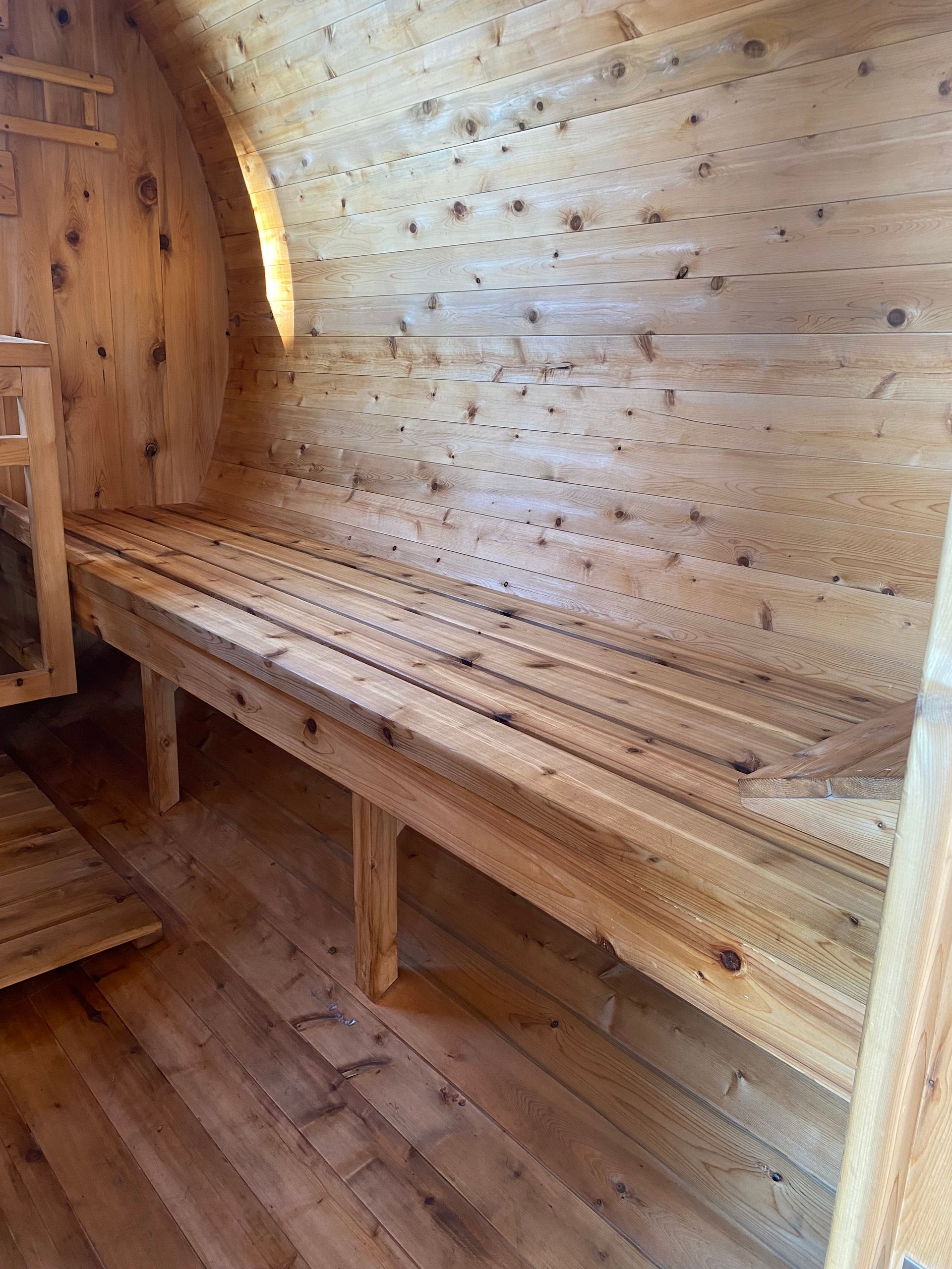 Wood-paneled sauna interior with curved bench seating and warm ambient lighting