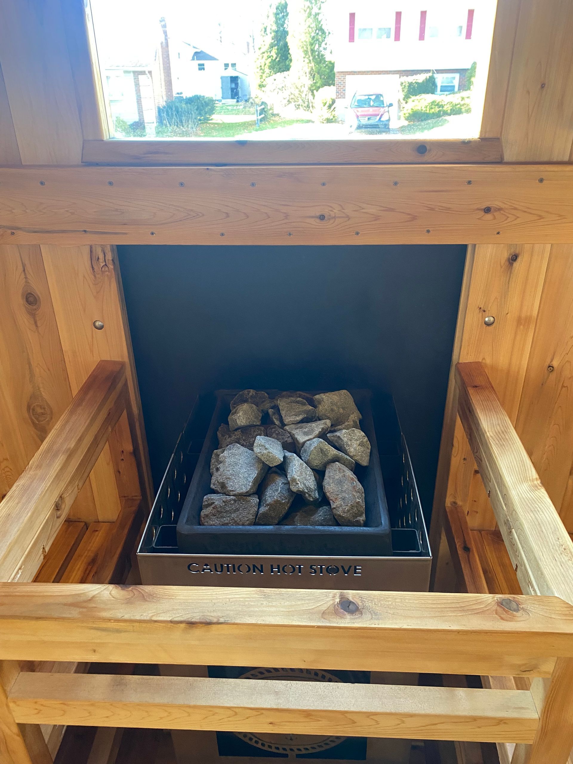 Wooden sauna heater with rocks inside and a small window above it