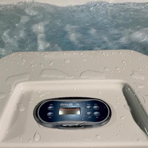 Hot tub control panel with water droplets, with bubbling water in the background