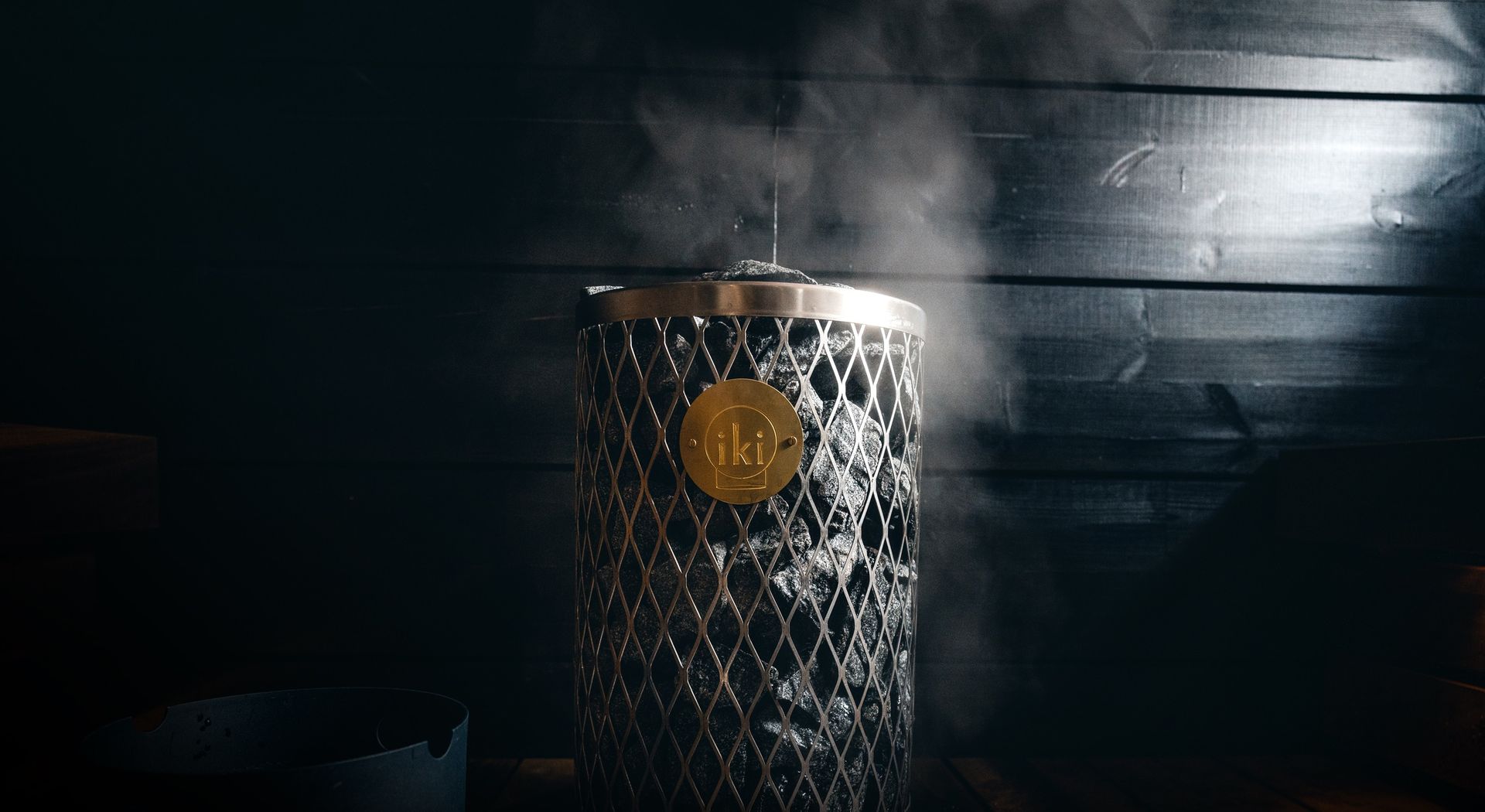 A silver cylindrical speaker with a gold circle glows against a dark, textured background.