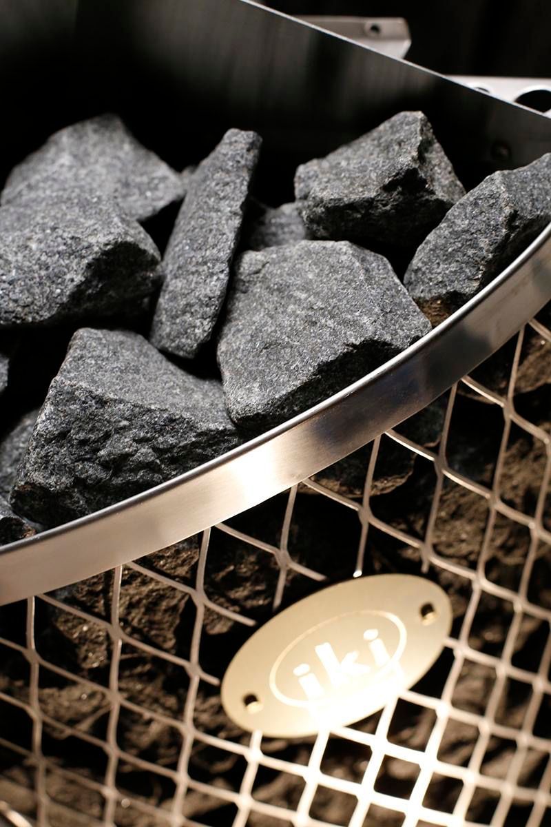 Charcoal briquettes piled in a metal grill basket over a wire mesh base