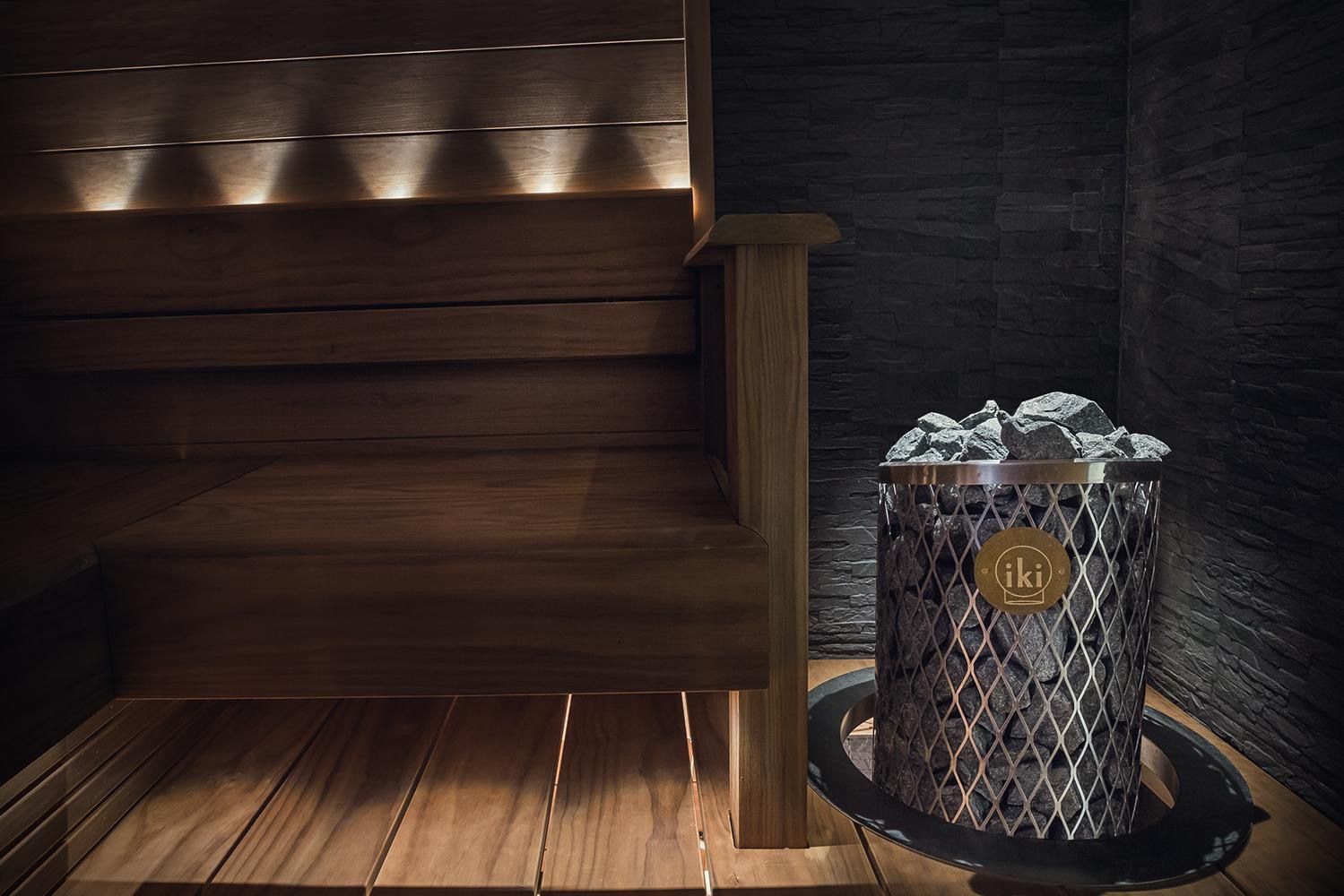 Metal bucket with steaming coals on a wooden table in a dimly lit sauna-like room