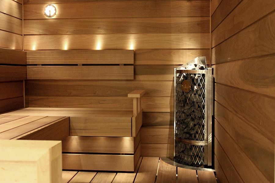 Wood-paneled sauna with bench seating and a glowing heater in the corner