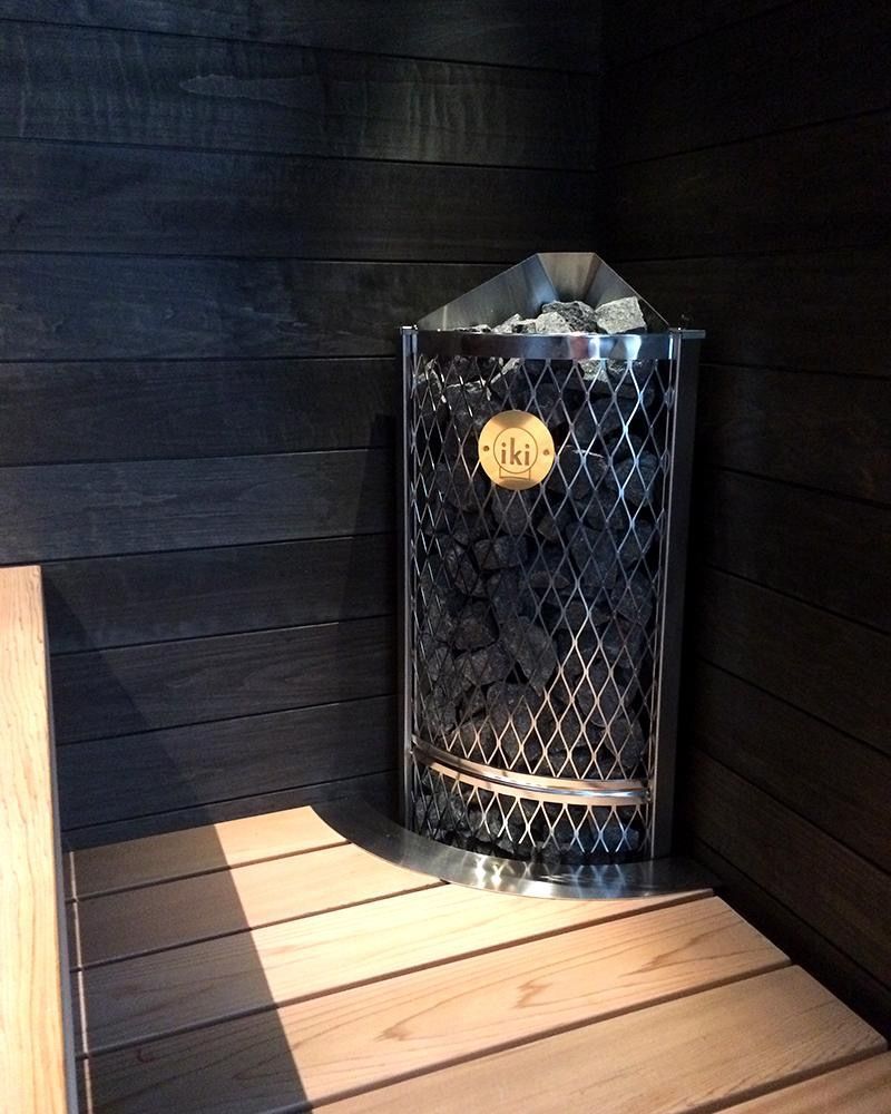 Black tiled shower stall with a rainfall showerhead and wooden floor.