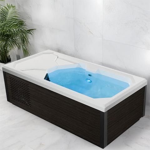 Modern rectangular hot tub with white rim, light blue water, and dark wood-paneled sides