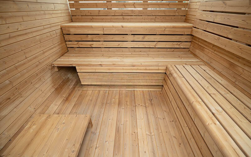 Wood-paneled sauna interior with tiered wooden benches and warm light