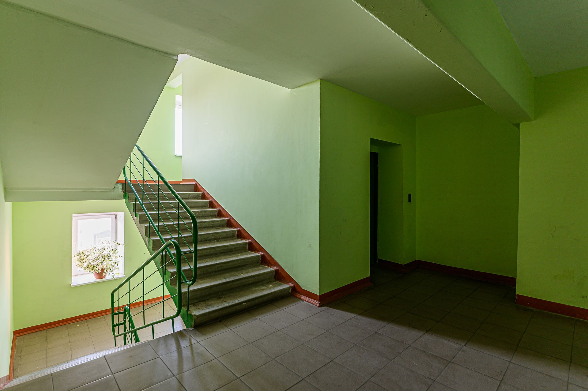 Ein leerer Flur mit grünen Wänden und Treppen in einem Gebäude.