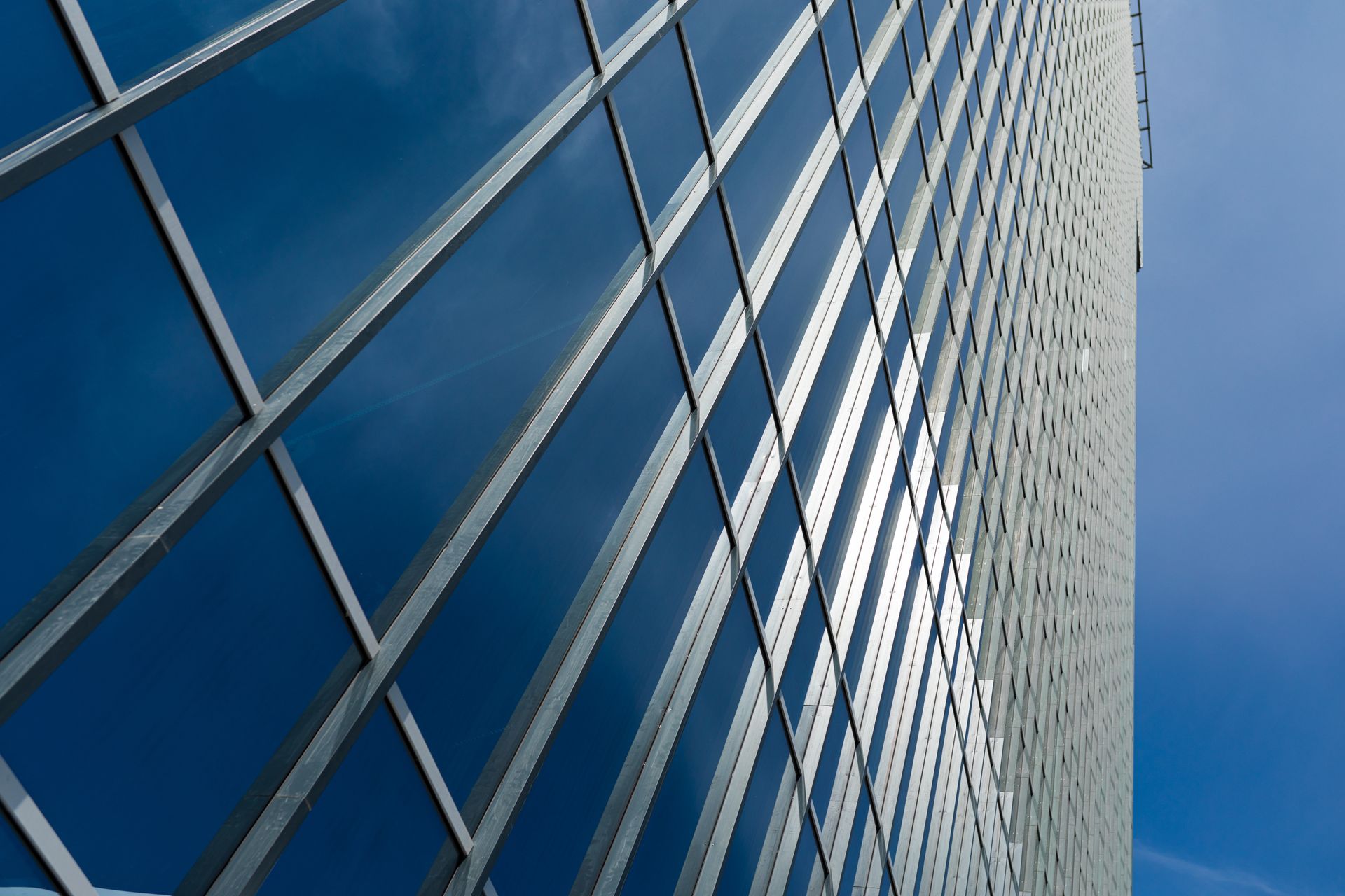 Modern glass building facade against a blue sky, viewed from below Modern glass building facade against a blue sky, viewed from below