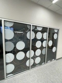 Glass wall panels with white and gold circle designs. Silver frames.