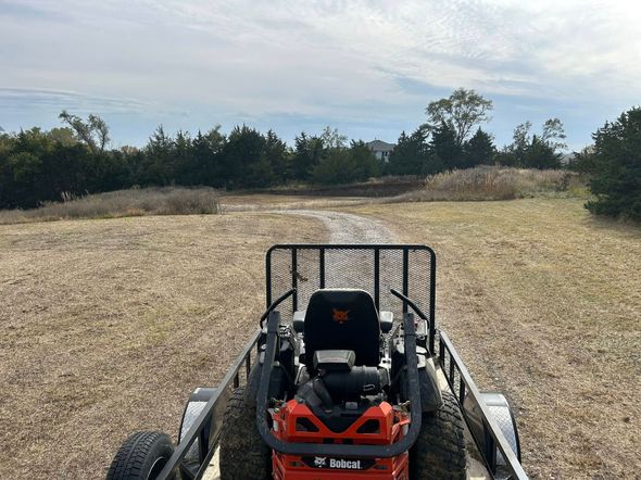Red lawn mower on a dry field with trees in the background