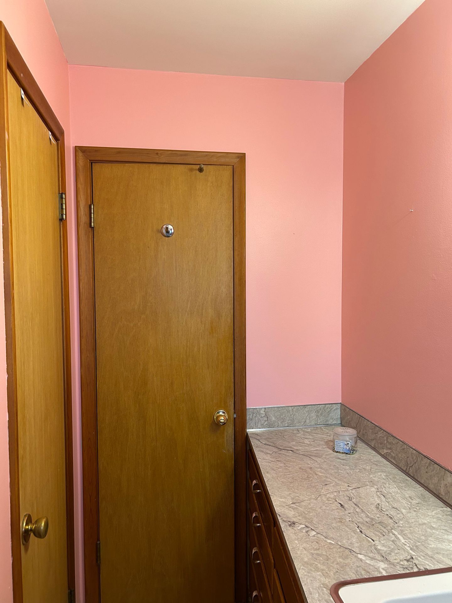 Narrow pink hallway with wooden doors and a granite countertop on the right.
