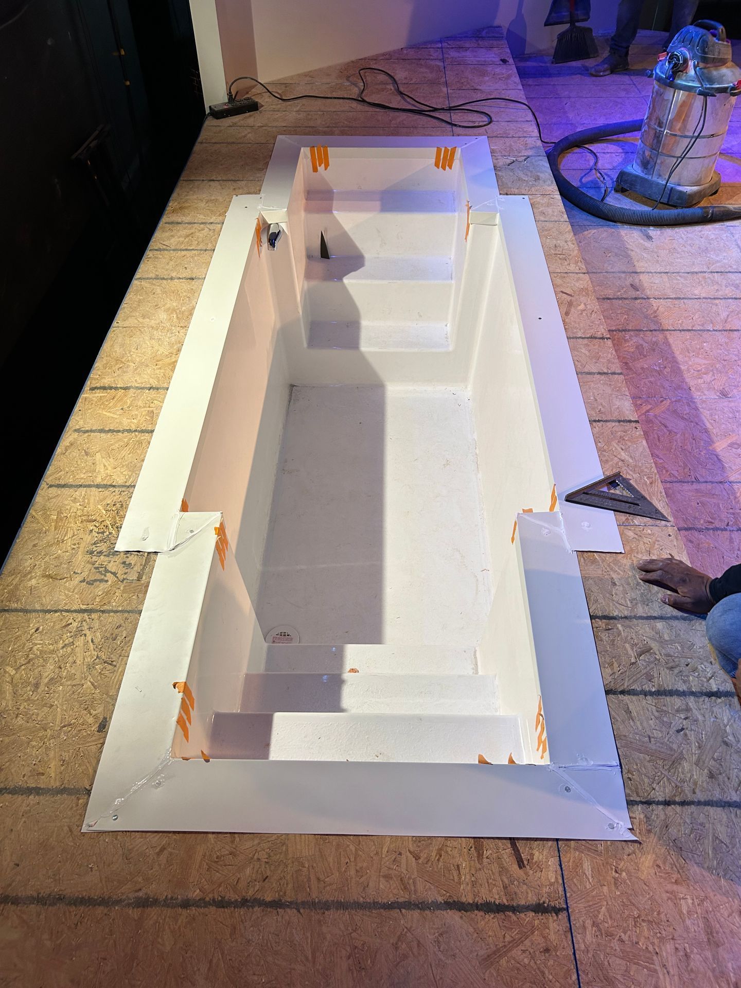 White foam model or mold on pavement, lit at night beside a stone fountain and curb.