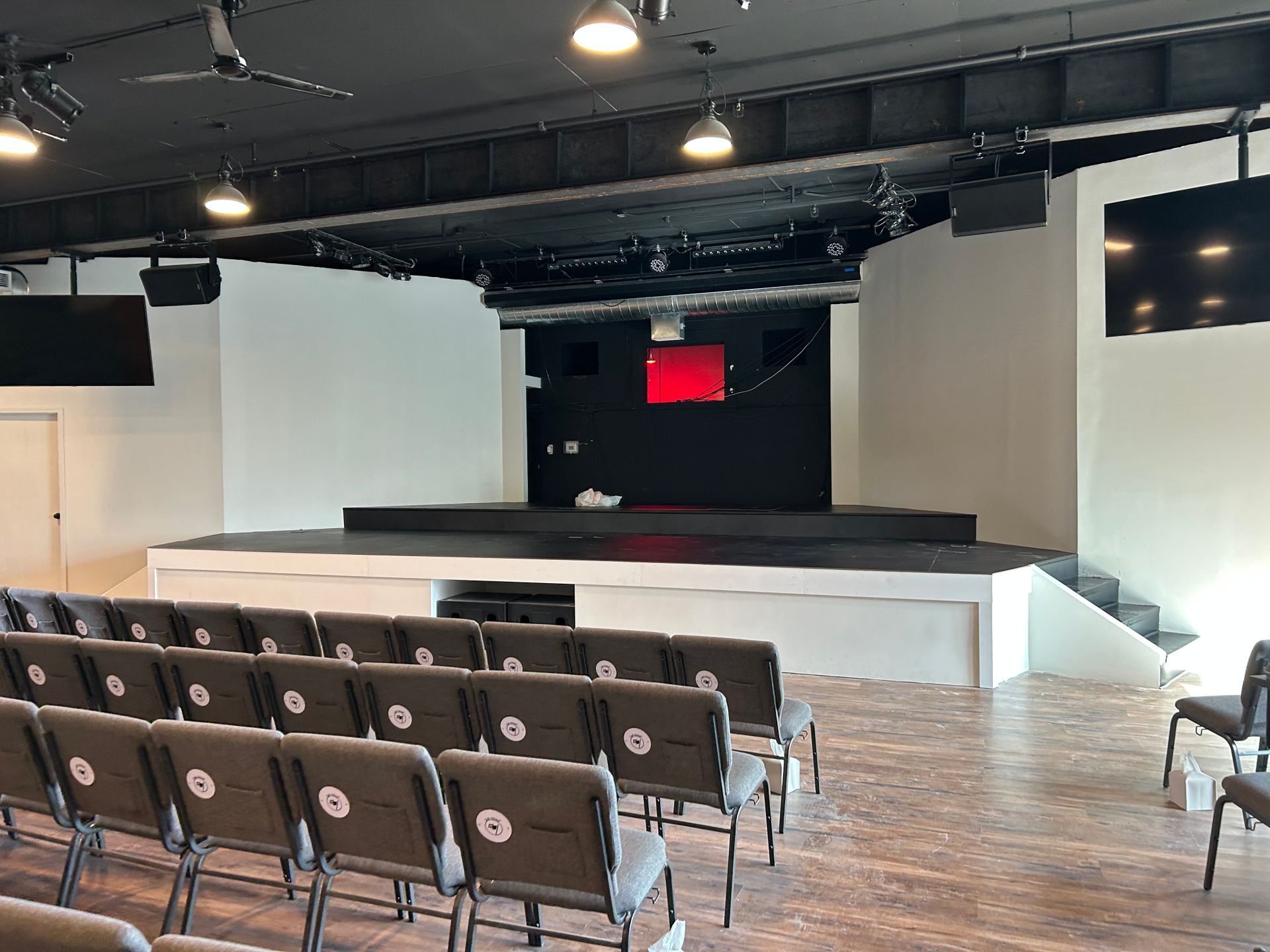 Auditorium with rows of chairs facing a stage and screen in a modern indoor venue