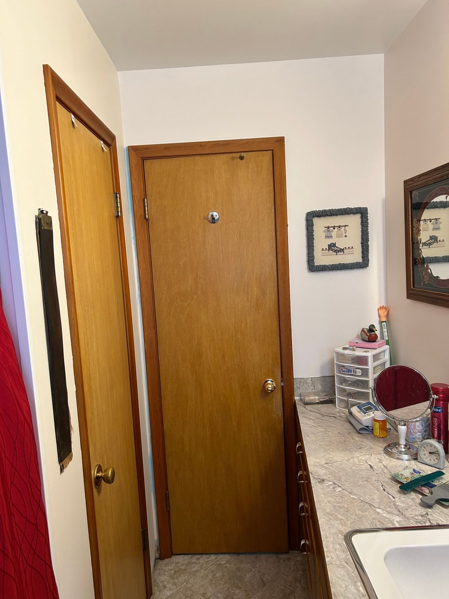 Narrow hallway with wooden doors, white walls, and a cluttered countertop along the right side.