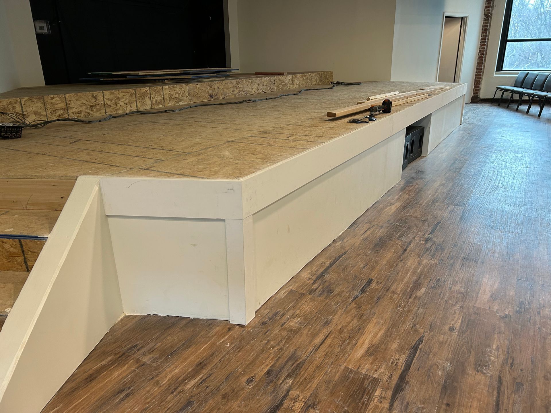 Built-in white seating wall beside a granite counter in a modern room with wood-look flooring