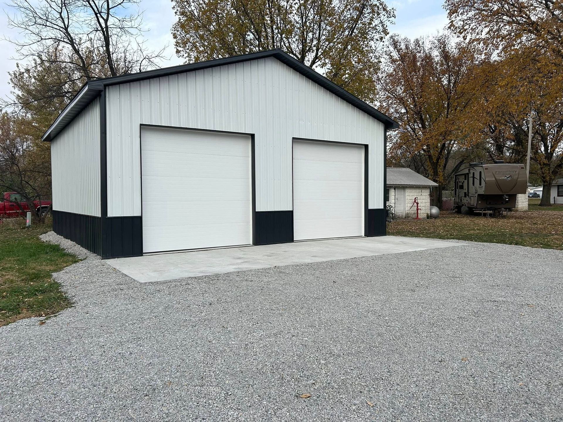 Detached white garage with two doors and gravel driveway in a rural yard