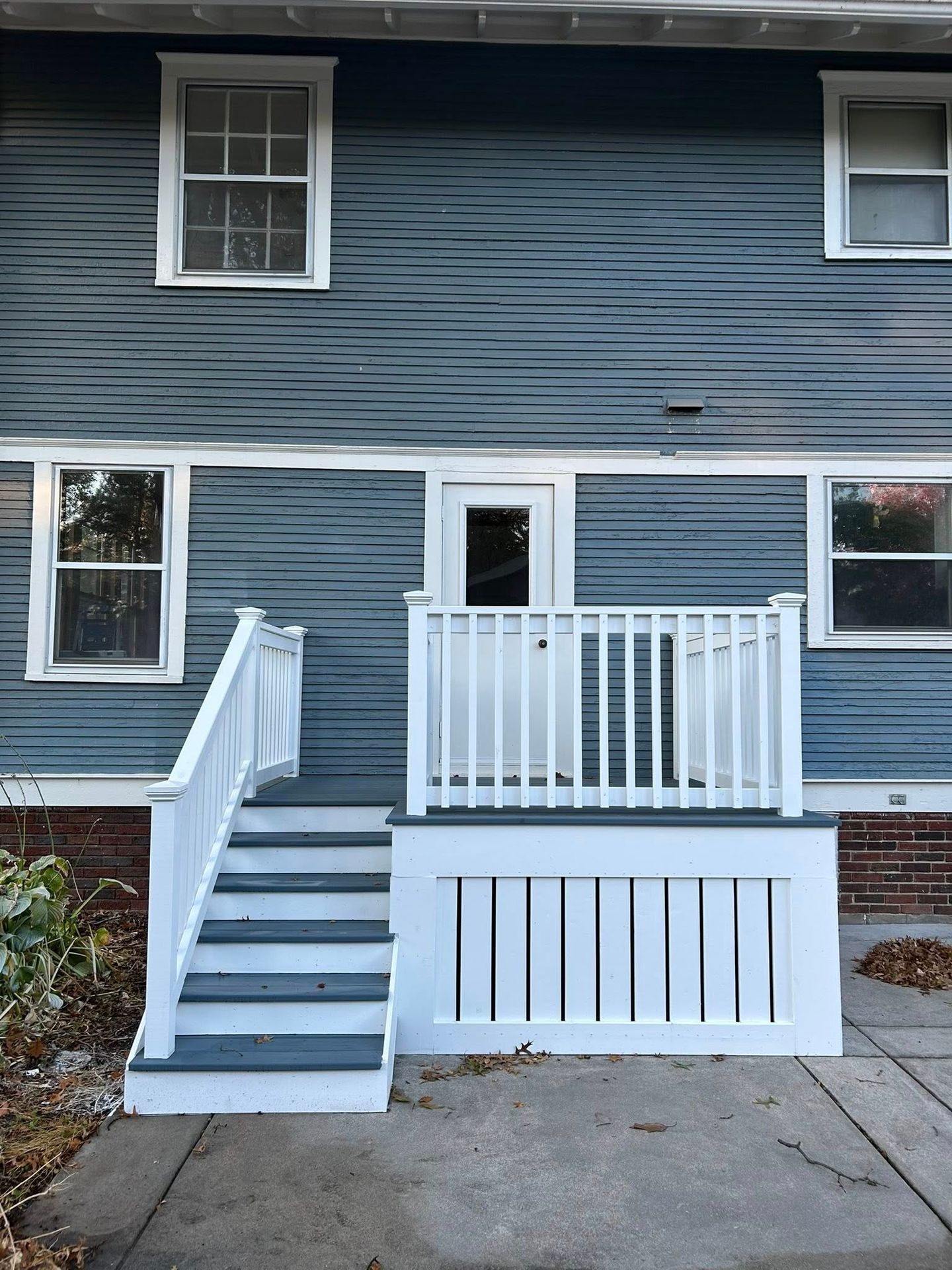 Front view of a blue house with white porch stairs and railing leading to the entrance