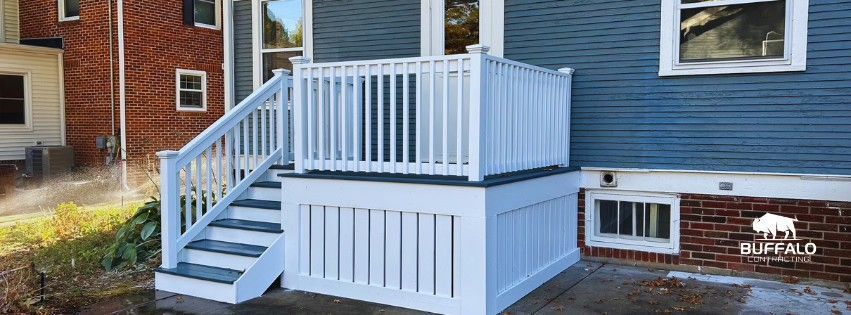 Blue house with white wheelchair-accessible ramp, stairs, and upper deck on the side of a home