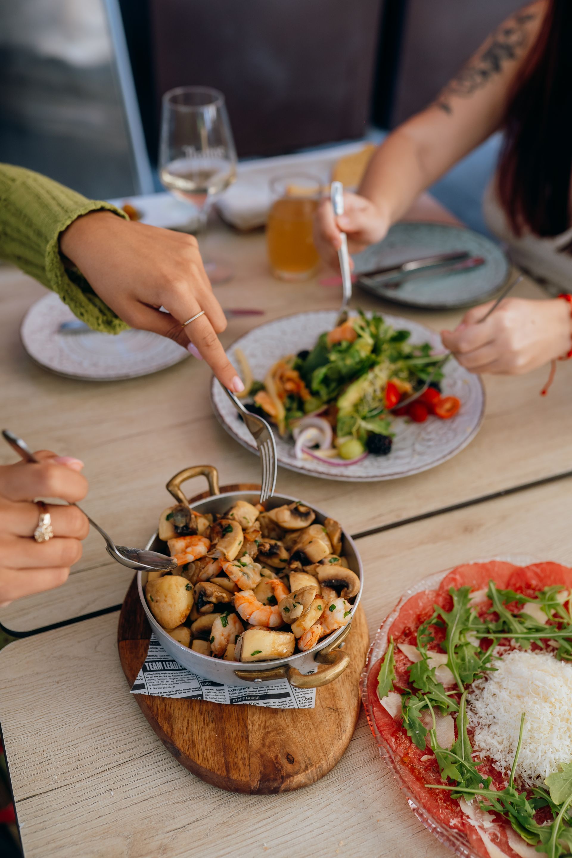 Personas compartiendo una comida al aire libre, con ensaladas y champiñones a la parrilla sobre una mesa.