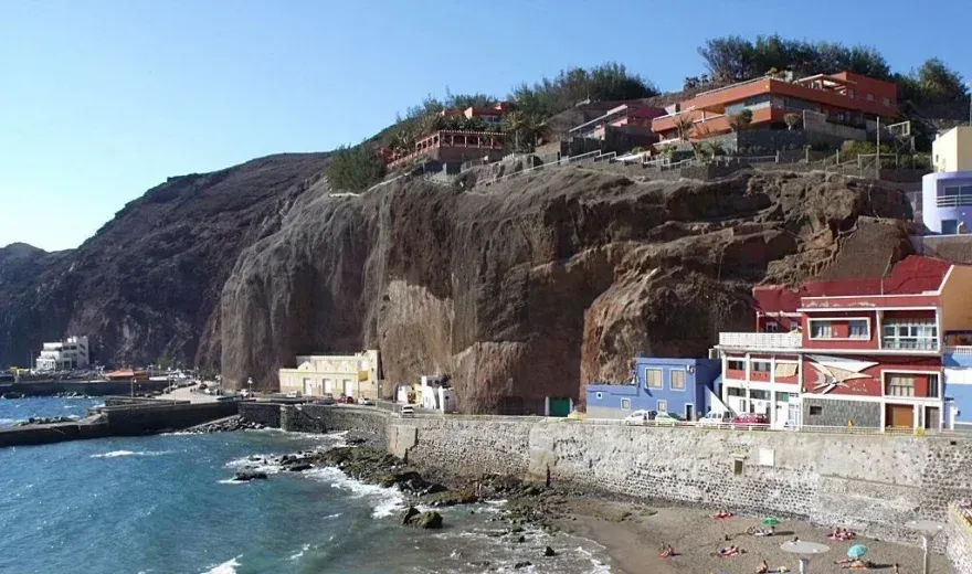 Acantilados rocosos junto al mar con edificios coloridos y un pequeño puerto junto al océano.