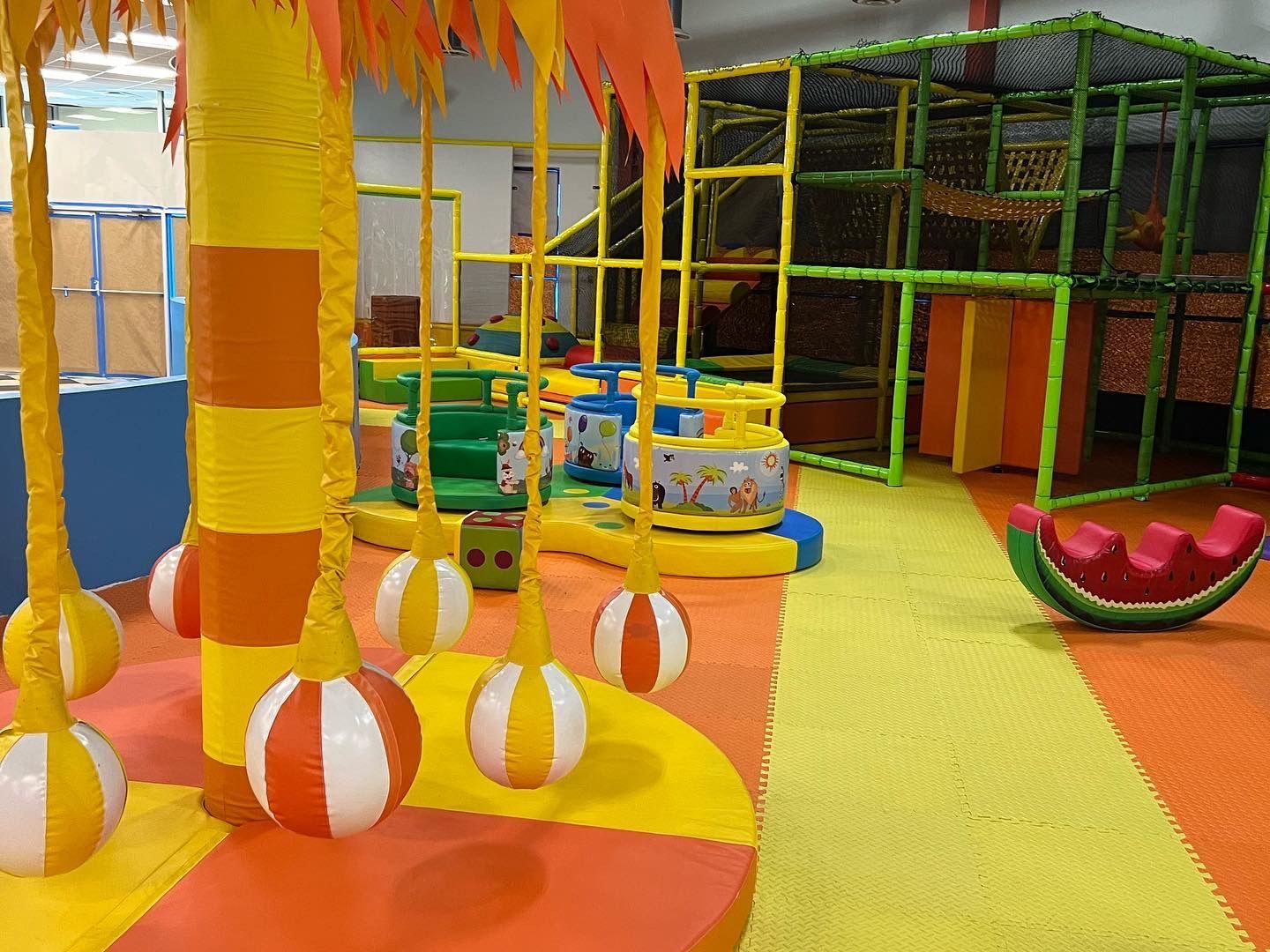 A children 's playground with balls hanging from trees and a watermelon swing.
