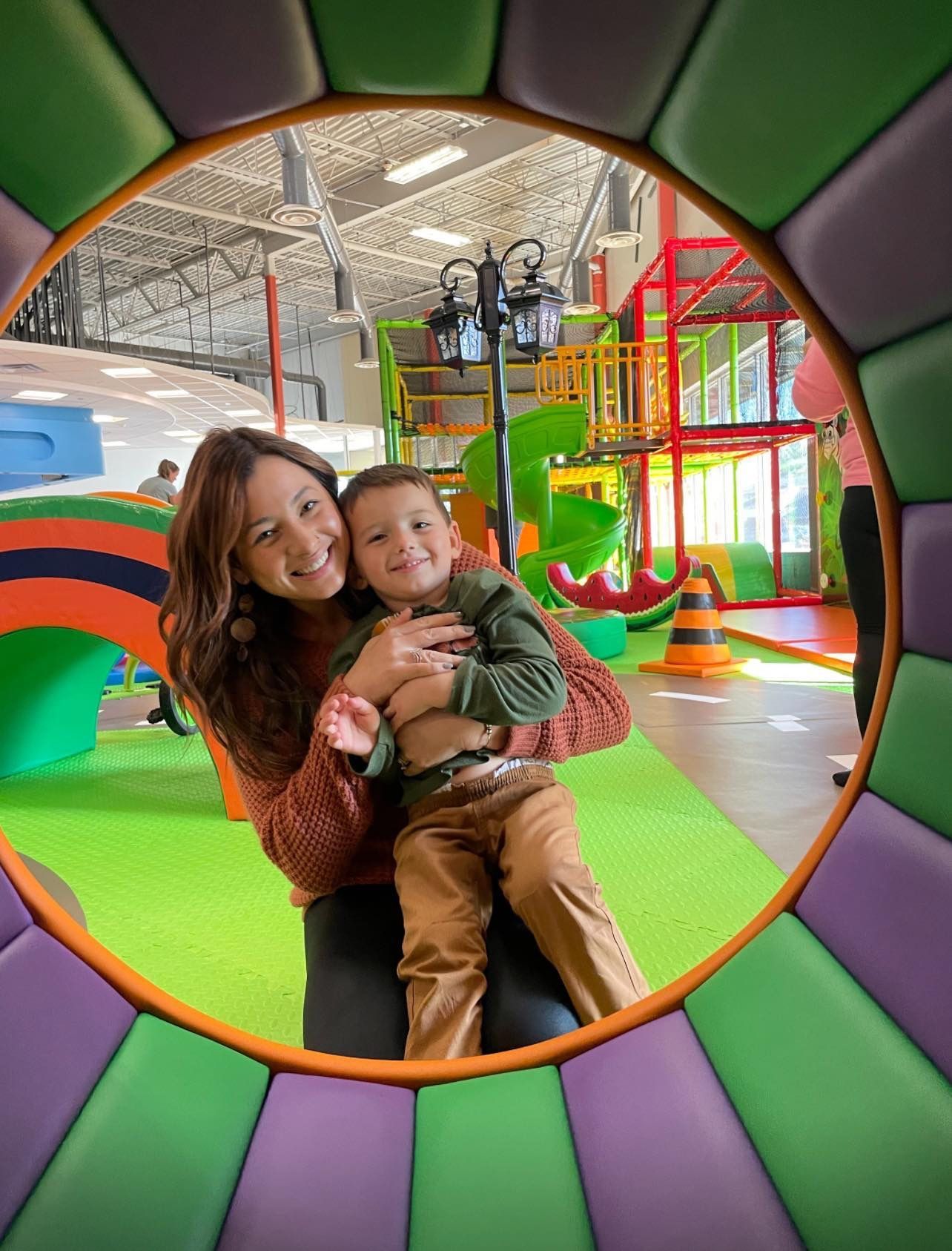 A woman is holding a child in her arms in a playground.
