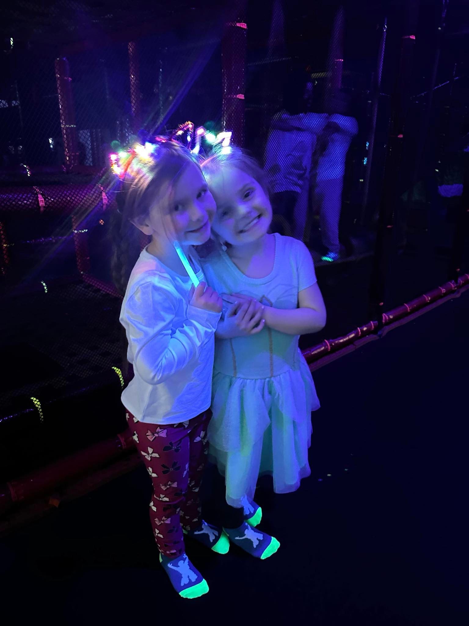 Two little girls are standing next to each other in a dark room.