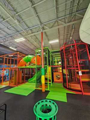 A large playground with a green trash can in the middle of it.