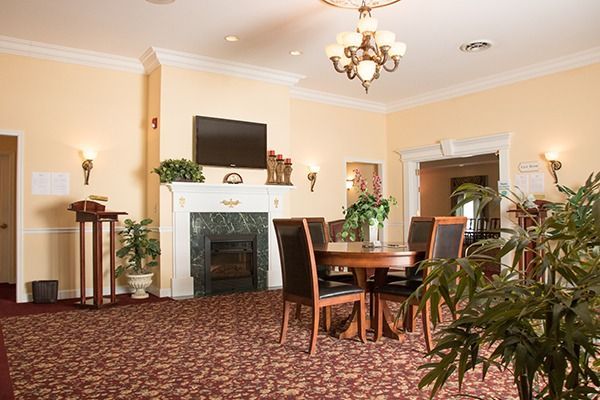 Elegant dining room with fireplace, wooden table, chairs, chandelier, and patterned carpet