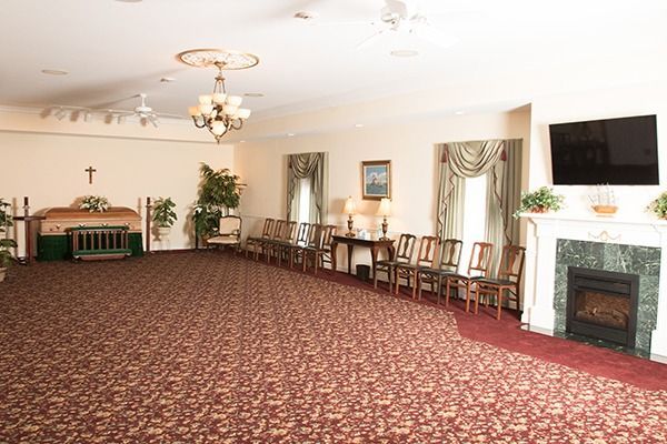 Empty banquet room with patterned carpet, rows of chairs, and a fireplace under wall-mounted TV.