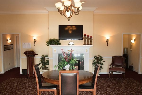 Elegant lobby seating area with round table, fireplace, chandelier, and wall sconces in warm tones
