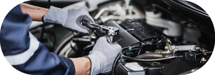 Mechanic working under a car hood with gloved hands in an auto repair shop | Clark's Tire & Automotive