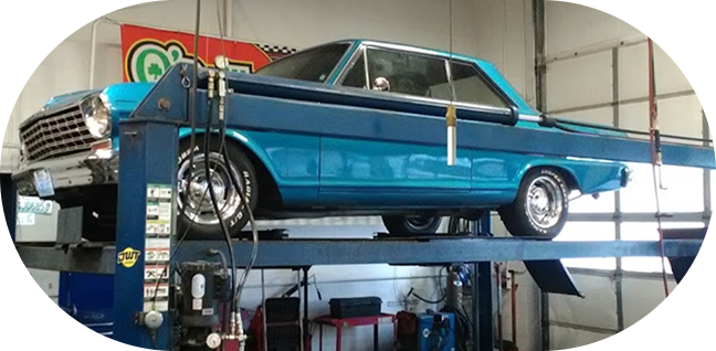 Blue classic car elevated on a vehicle lift in a garage  | Clark's Tire & Automotive