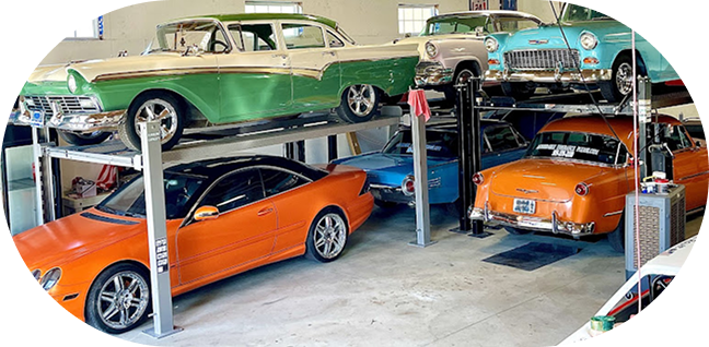 Classic cars displayed in a garage: green vintage sedan above orange sports cars and a turquoise car | Clark's Automotive