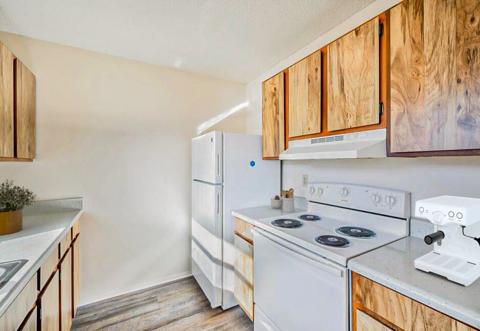 Kitchen with light wood cabinets, white appliances, and a light-colored countertop.