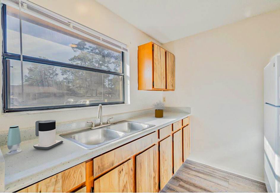 Kitchen with wooden cabinets, a sink, a window, and a refrigerator.