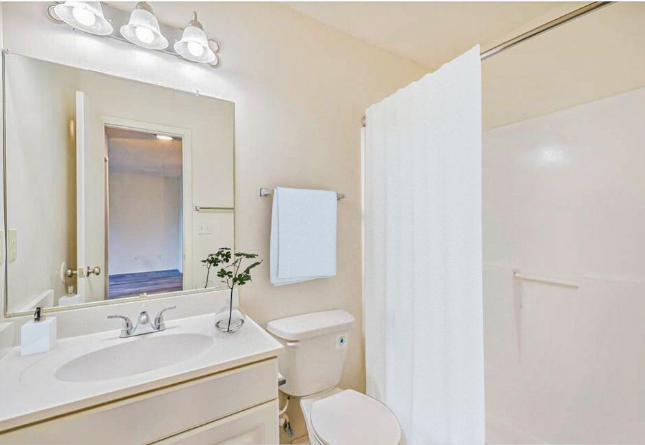 Bathroom with white fixtures, vanity, toilet, shower, and a white curtain.