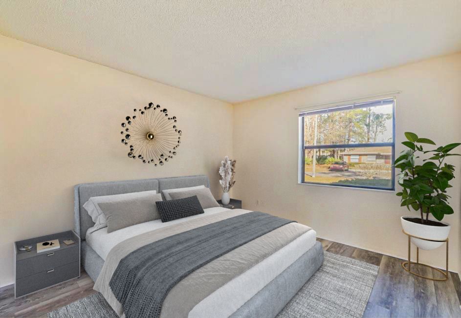 Bedroom with a bed, nightstand, window, decorative wall art, and a potted plant.