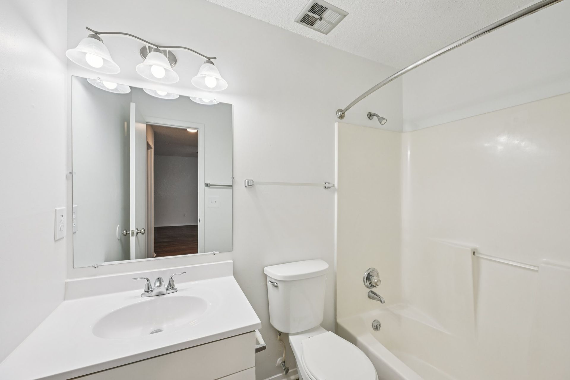 Bathroom with white vanity, toilet, and bathtub/shower.