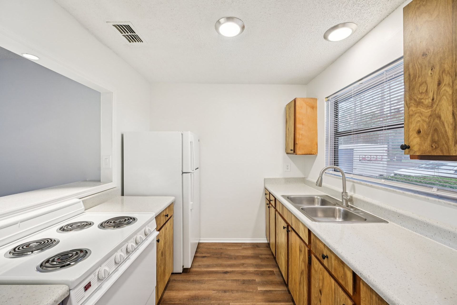Kitchen with white appliances, wood cabinets, and light countertops.