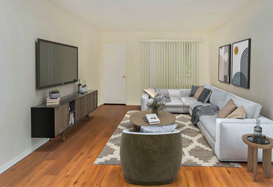 Living room with a white sectional, a rug, TV, and art.