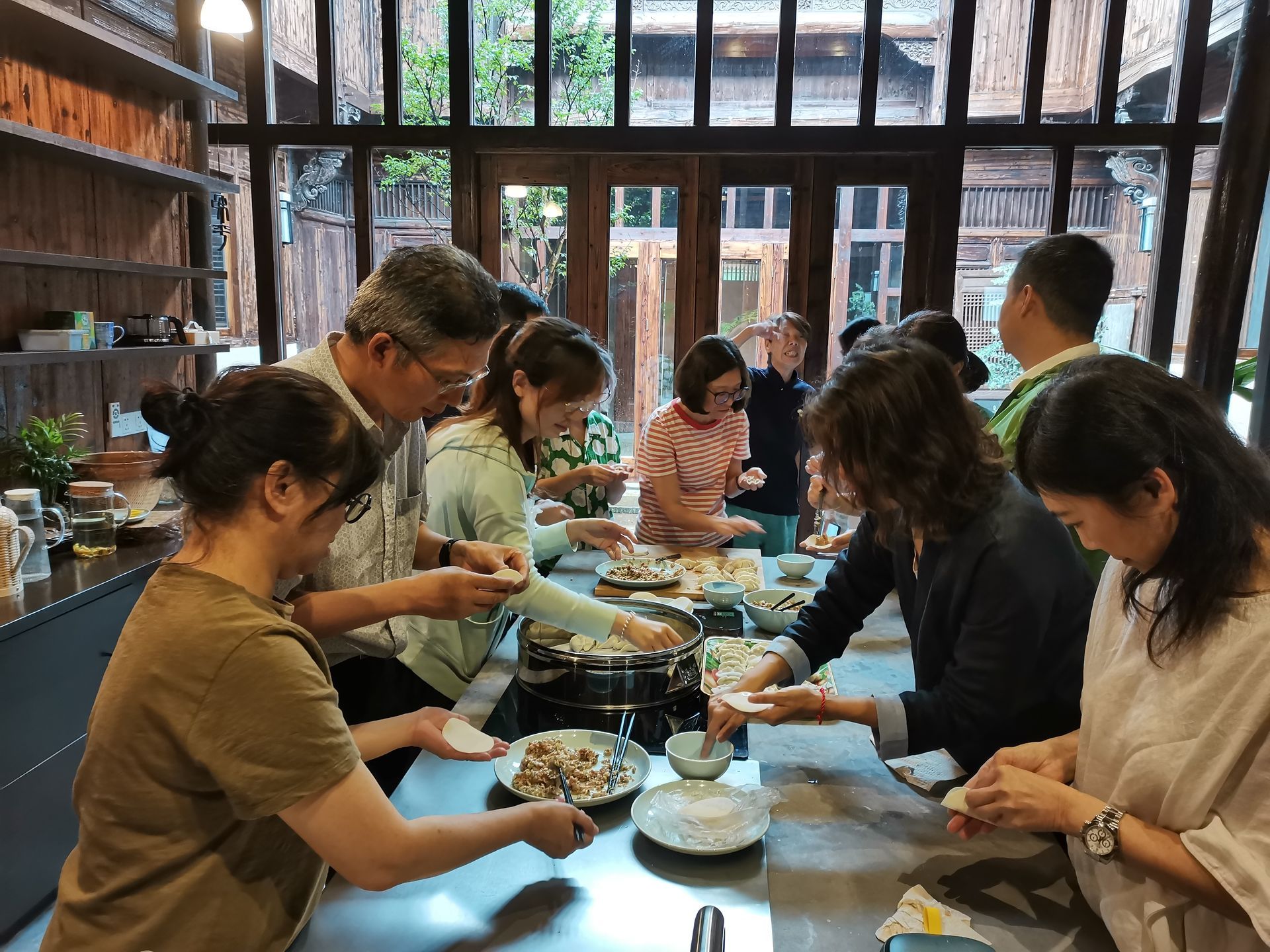 People sharing a meal and preparing food at a long table in a bright dining room
