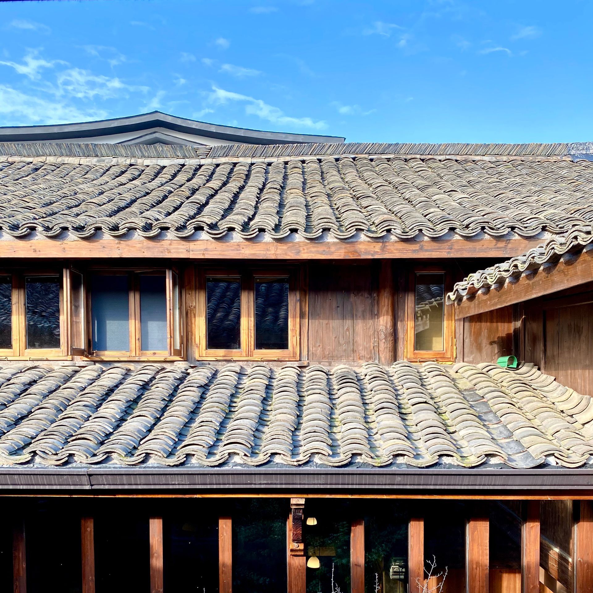 Traditional wooden building with layered gray tile roofs under a bright blue sky