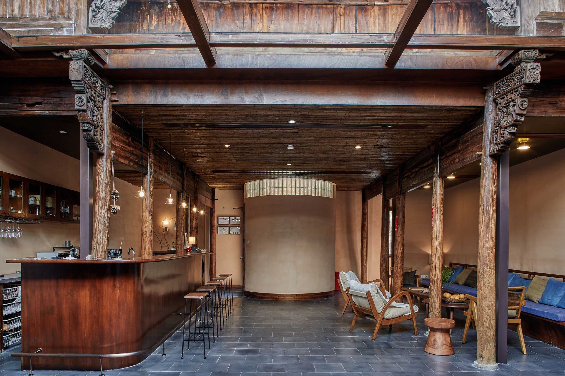 Rustic hotel lobby with wood beams, stone columns, bar counter, seating, and warm lighting