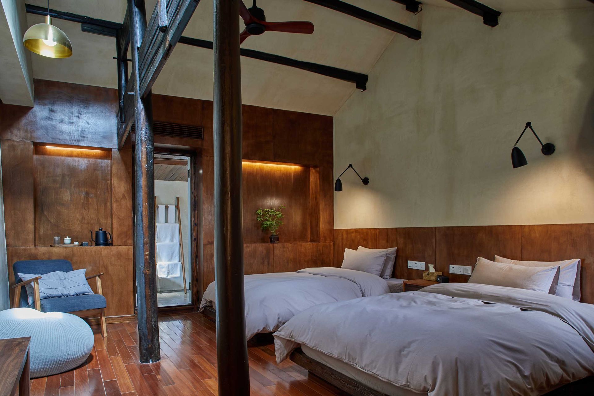 Rustic bedroom with wooden beams, two beds, and warm wood-paneled walls