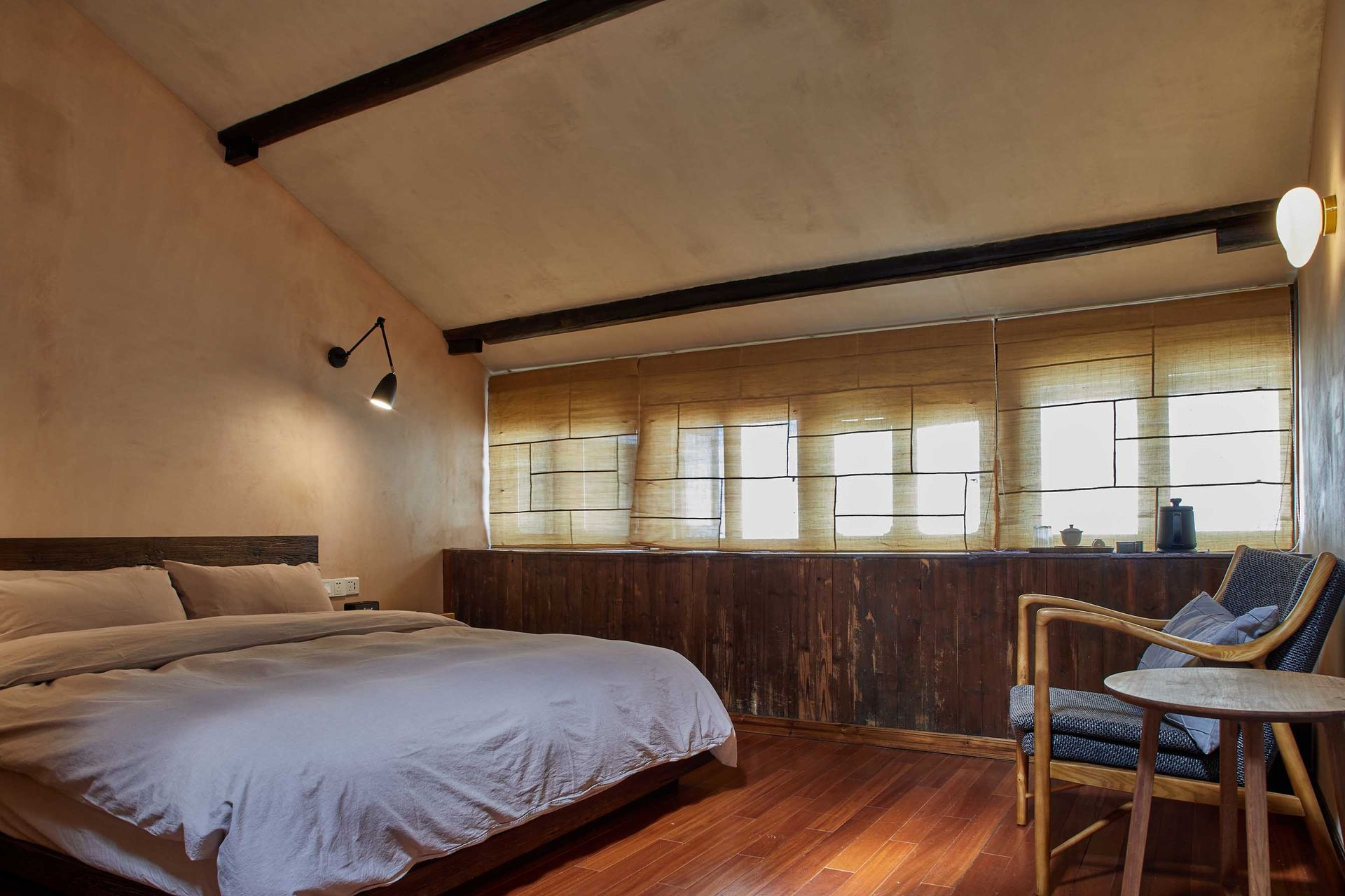 Cozy bedroom with a large bed, wooden floor, and sunlit window seating area