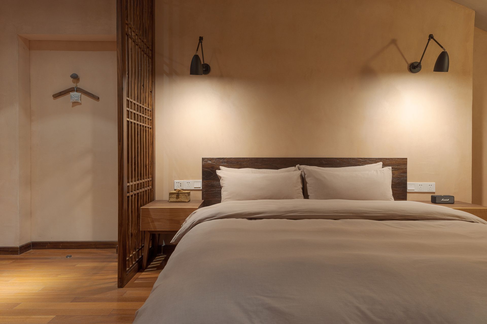 Modern hotel bedroom with a neatly made bed, warm lighting, and wooden accents